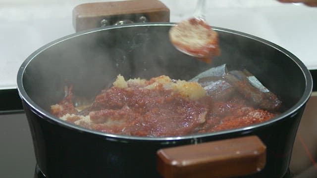Cooking fish in a pot, adding spices with a spoon