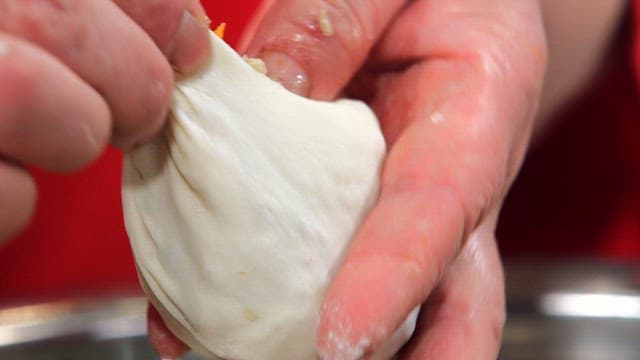 Hands shaping dough into a dumpling