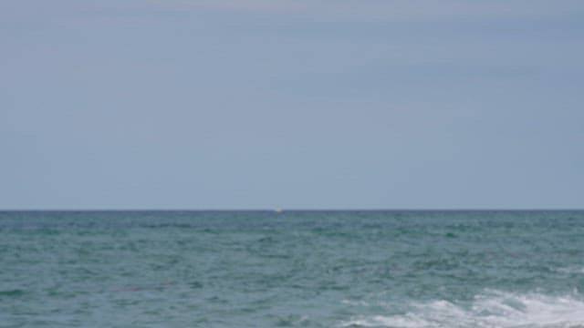 Serene Sea and a Distant Boat Floating on the Horizon