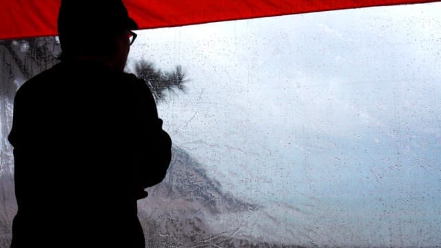 Silhouette of a person looking out at rainy weather from inside a tent