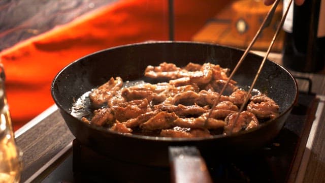 Grilling sizzling meat on a hot frying pan with oil