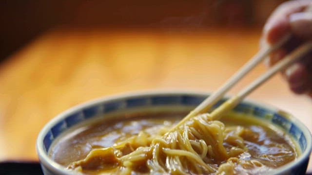Chopstickful of steaming curry noodles in a bowl