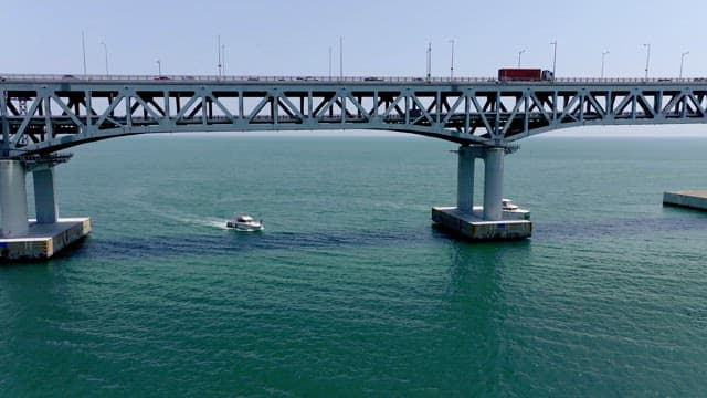 Yachts passing under the Gwangan Bridge on a clear day with lots of cars