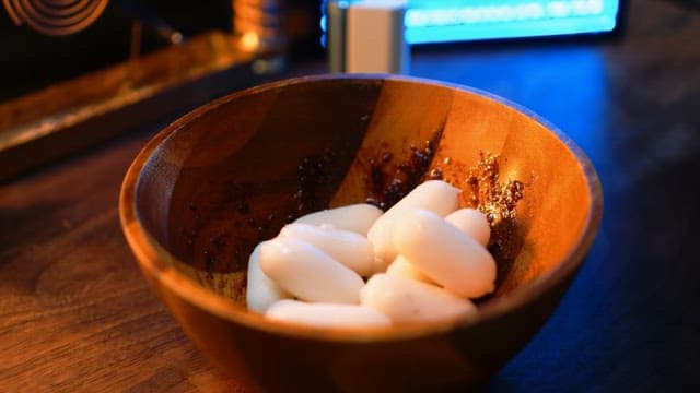 Adding white rice cakes to a wooden bowl and mixing them with seasoning
