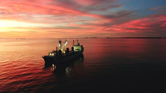 Sky full of red sunset over the sea with a fishing boat