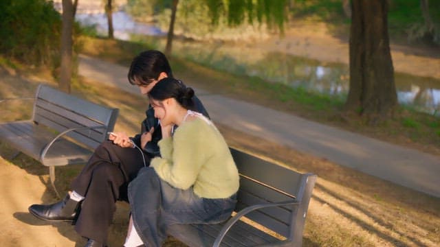 Couple checking their smartphones on a park bench