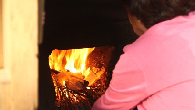 Person lighting a fire with firewood in an old kitchen stove