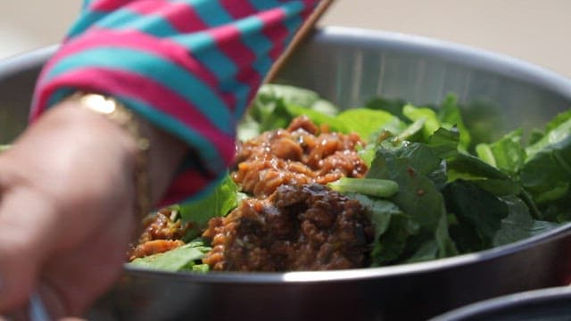 Mixing soybean paste and fresh young radish leaves in a bowl