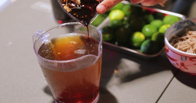 Pouring sauce into a pitcher in a kitchen