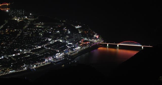Riverside Cityscape at Night with Illuminated Bridge
