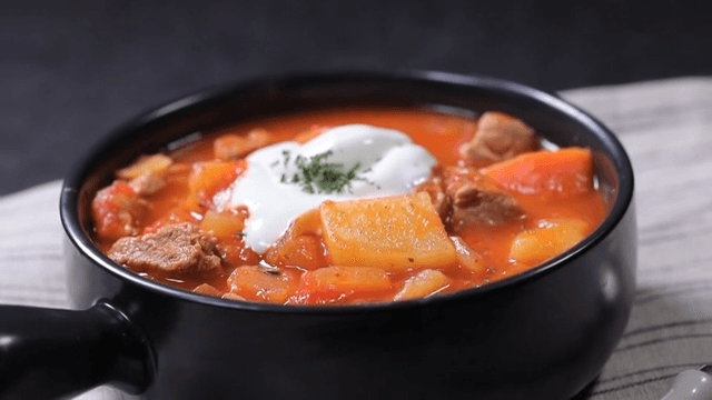 Bowl of hearty pork stew with sour cream