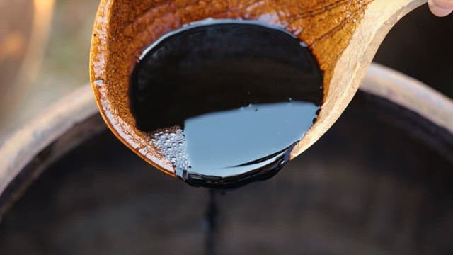 Pouring Soy Sauce from a Wooden Bowl