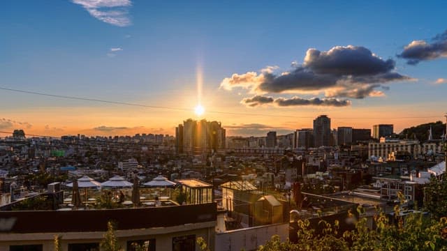 Sunset over a vibrant city skyline with glowing skyscrapers and a busy rooftop restaurant