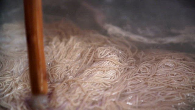 Noodles boiling in a pot with steam