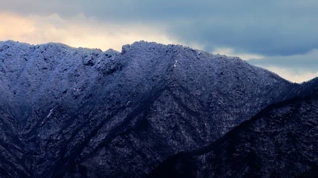 Snow-covered mountains under cloudy skies