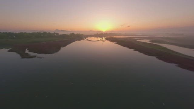 Serene river at sunrise with a bridge