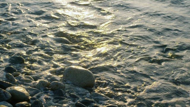 Sunset reflections on a pebbly seaside