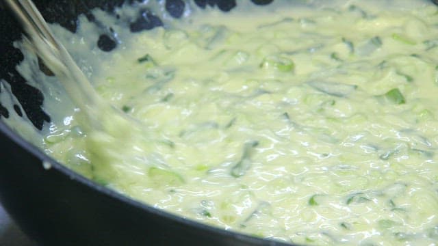 Mixing the batter with green onions in a frying pan