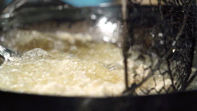 Frying meat in hot oil in a wok in the kitchen