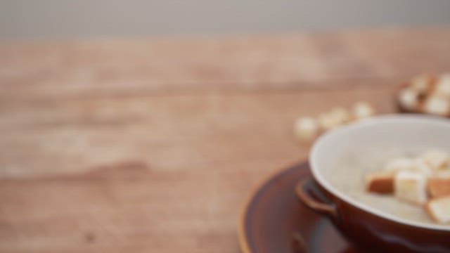 Bowl of button mushroom soup topped with toasted bread crust