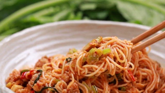 Bowl of spicy young radish bibim noodles with a chopstick