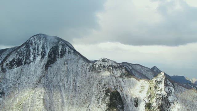 Snowy Mountain Peaks under Cloudy Sky