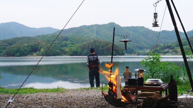 Two people camping by the lakeside surrounded by mountains