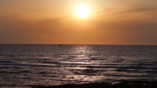 Sunset over the ocean with a distant boat
