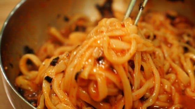 Picking up spicy and sour bibim noodles with chopsticks