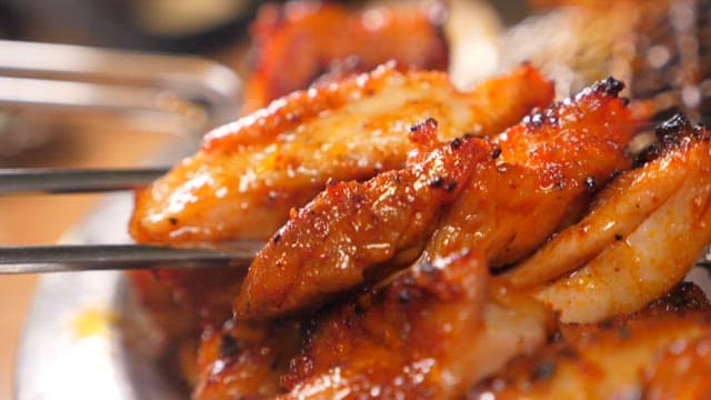 Spicy charcoal-grilled chicken held with chopsticks