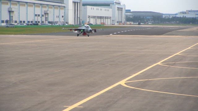 Fighter jet taxiing on a runway near aircraft hangars