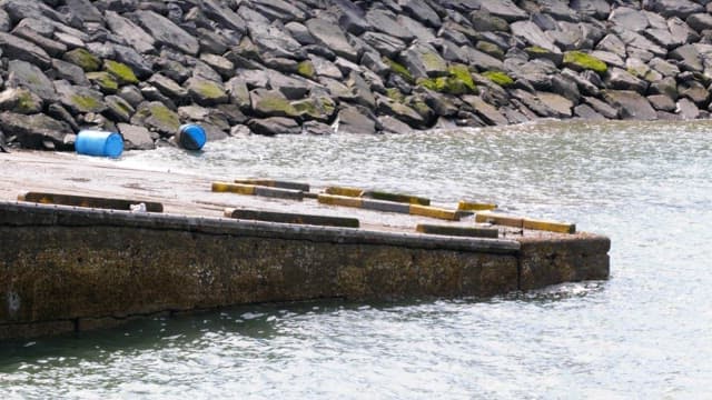 Green mossy rocky pier with gentle waves