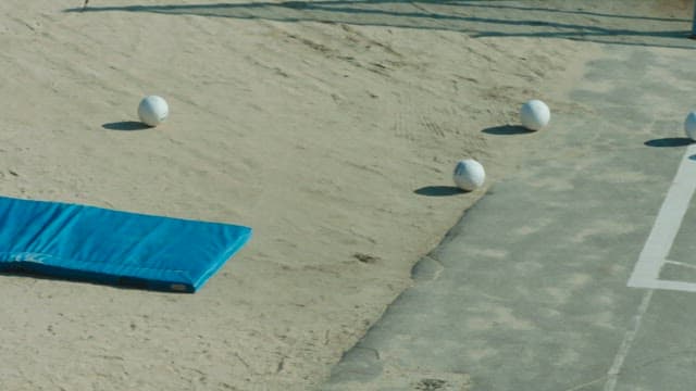 White volleyball balls and blue mats on the sandy schoolyard