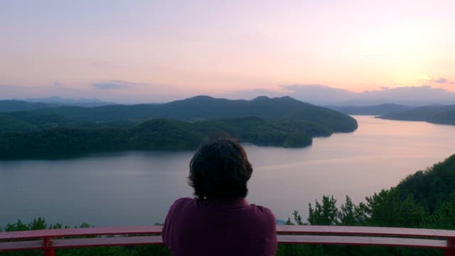 Person enjoying a serene lake view at sunset