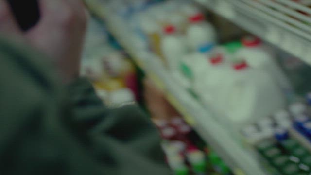 Customer shopping while on a phone call inside a convenience store at night