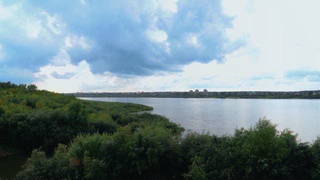 Riverbank with an overcast sky beside a city