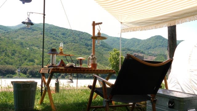 Camper relaxing under a shade near mountains and river