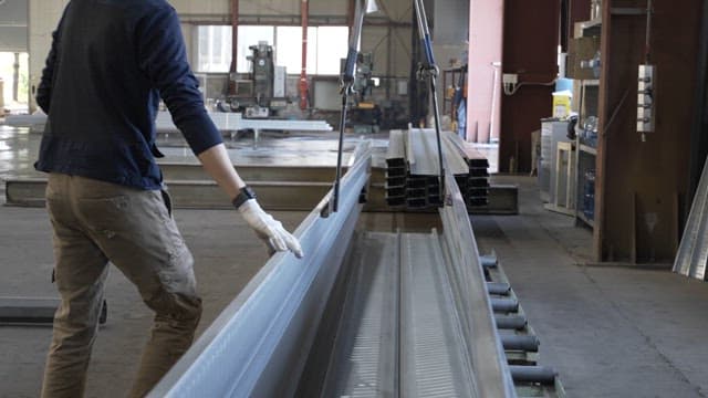 Worker handling metal beams in a factory