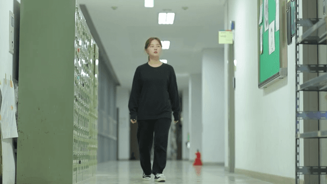 College student walking down a hallway with lockers and bulletin boards