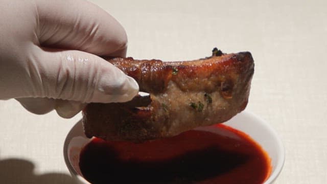 A piece of meat being dipped in sauce