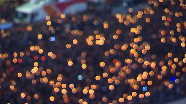 Crowd gathering at dusk with candles