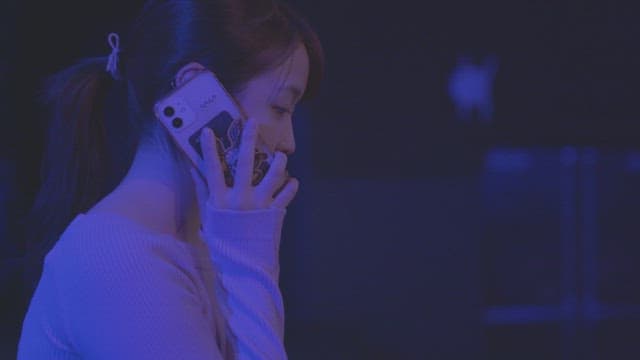 Woman in a dimly lit room having a phone conversation