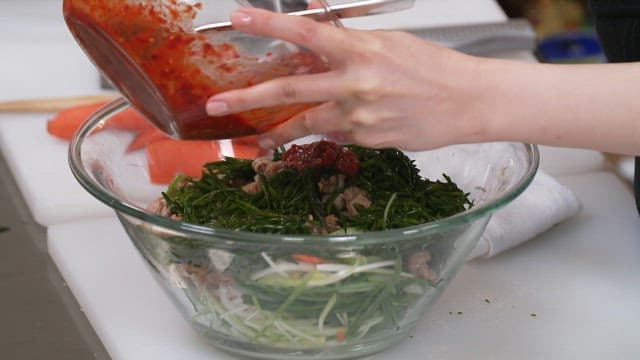 Adding spicy sauce to a fresh hijiki seasoned salad