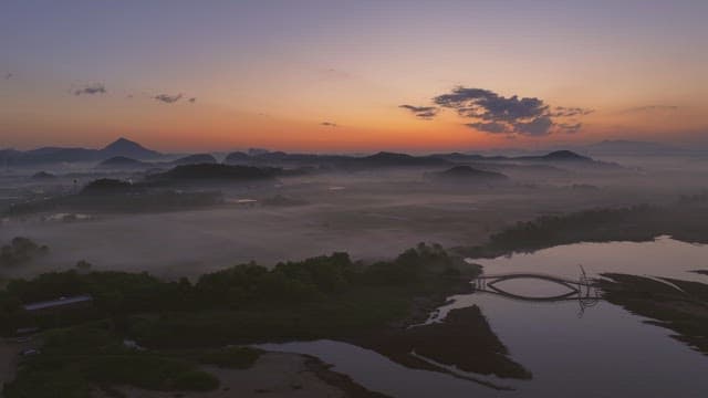 Serene river with misty mountain at sunset