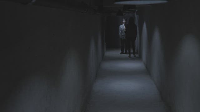Man and woman having a serious conversation in a dimly lit hallway