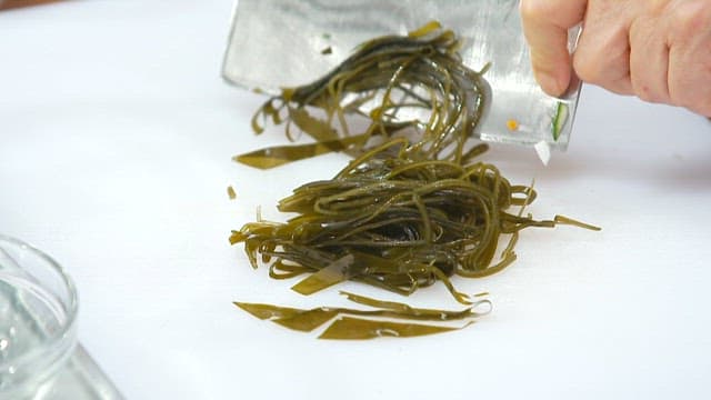 Chopping kelp on a cutting board and adding it to kalguksu