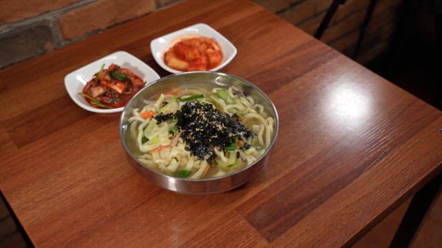 Kalguksu with kimchi on a wooden table