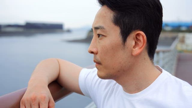 Man in white shirt looking at the sea