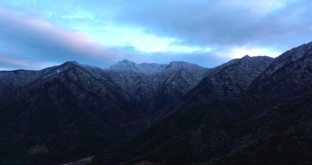 Snow-covered mountains under cloudy skies