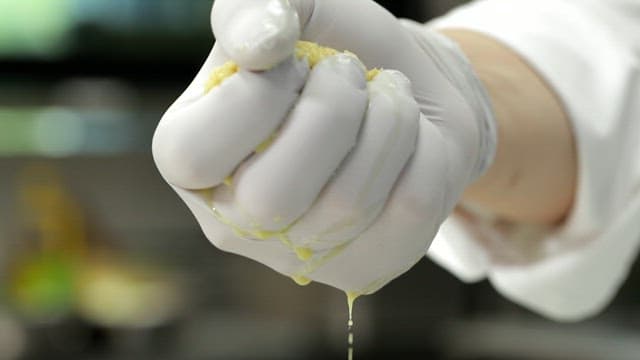 Squeezing ginger juice with gloved hands in the kitchen